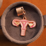 Front view of a uterus anatomy stethoscope charm in a warm gray velvet gift box